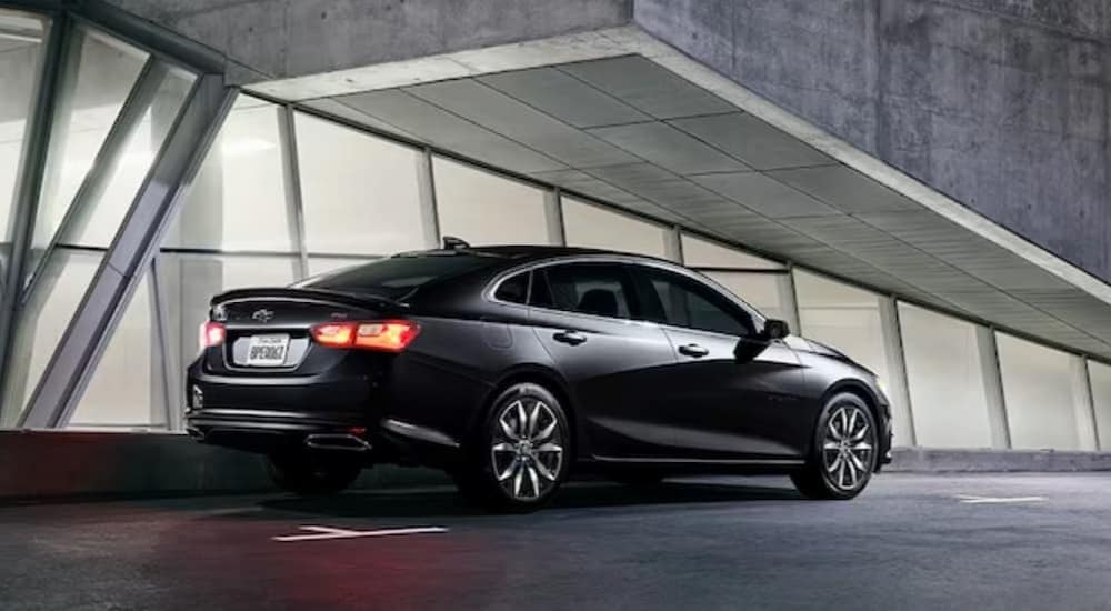 A black 2024 Chevy Malibu Midnight Edition is shown parked on a parking spot.