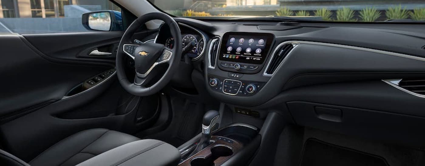 The black interior of a 2024 Chevy Malibu is shown from the passenger side.