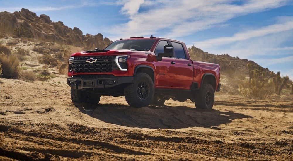 A red 2024 Chevy Silverado 2500 HD ZR2 Bison is shown parked off-road.