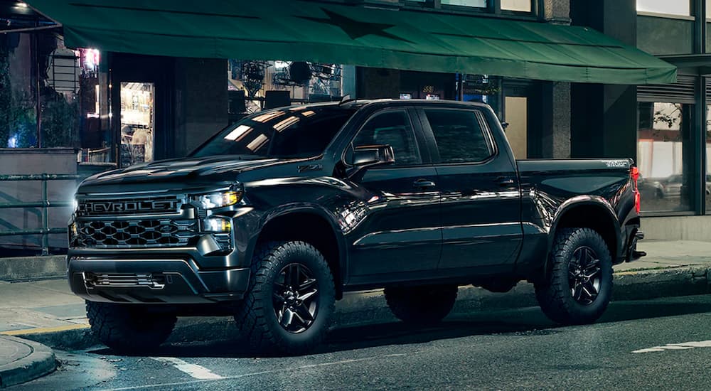 A black 2024 Chevy Silverado 1500 Z71 Trail Boss parked on a city street at night.