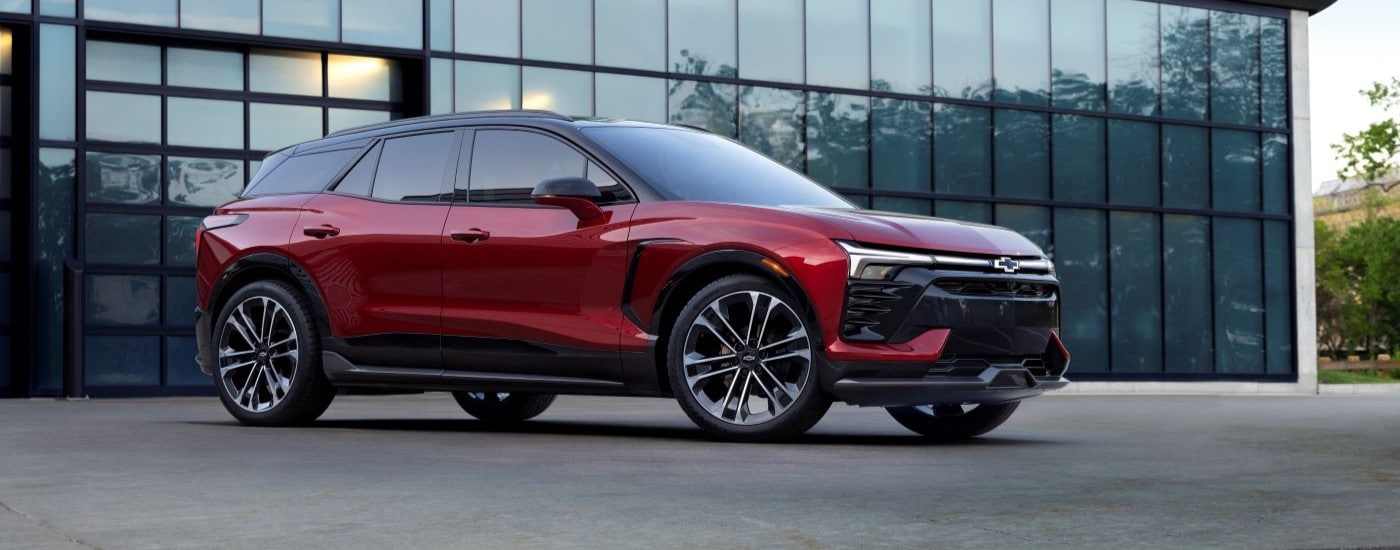 A red 2024 Chevy Blazer EV SS parked in front of a modern building.