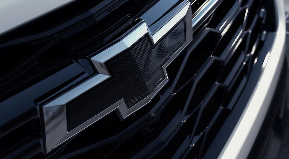 Close up of the grille and badge on a white 2023 Chevy Traverse.