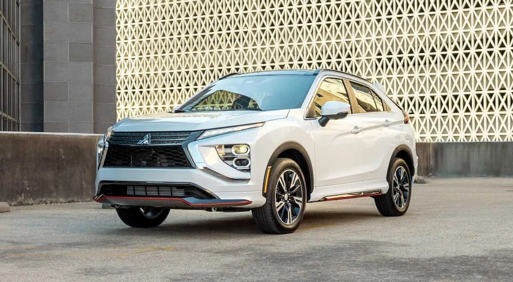 A white 2023 Mitsubishi Eclipse Cross on the roof of a parking garage in front of an intricately patterned wall.