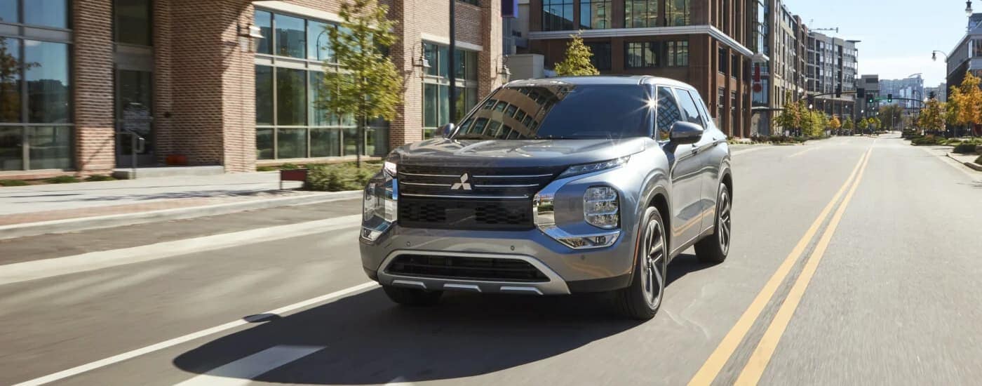 A silver 2023 Mitsubishi Outlander driving on a city street after visiting a Fort Washington, MD Mitsubishi dealer.