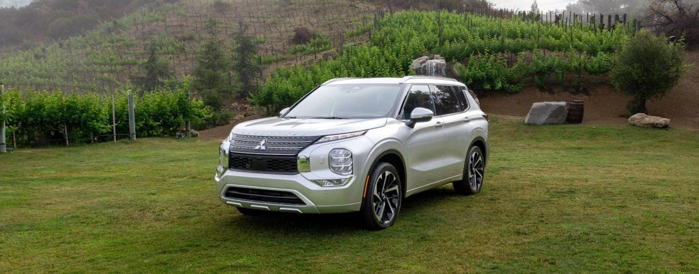 A silver 2024 Mistibishi Outlander is shown from the front at an angle in a field after leaving a Mitsubishi dealer near Springfield.