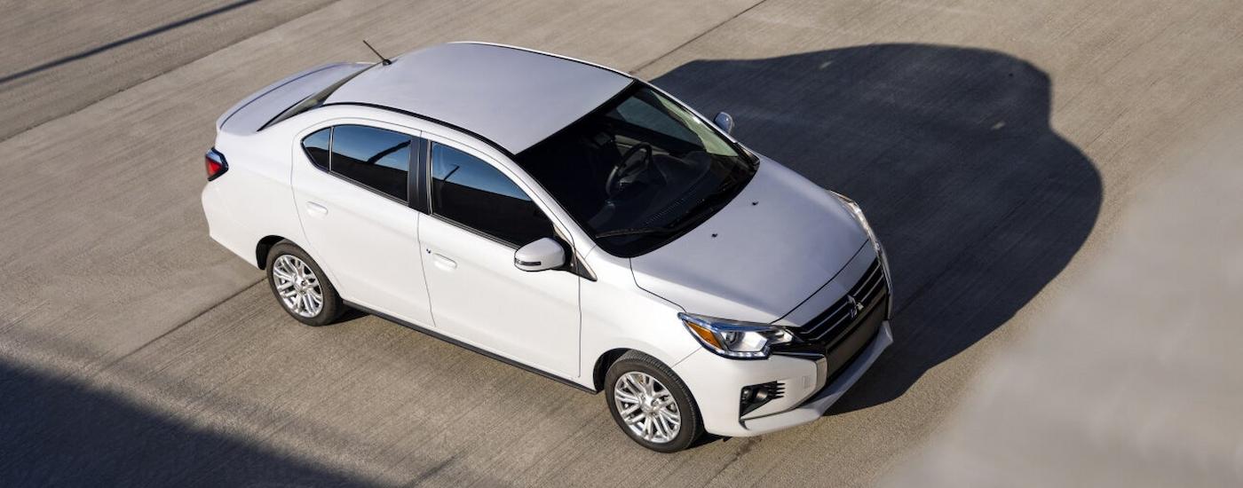 Aerial view of a white 2022 Mitsubishi Mirage G4 parked in an empty lot near a Mitsubishi dealer.