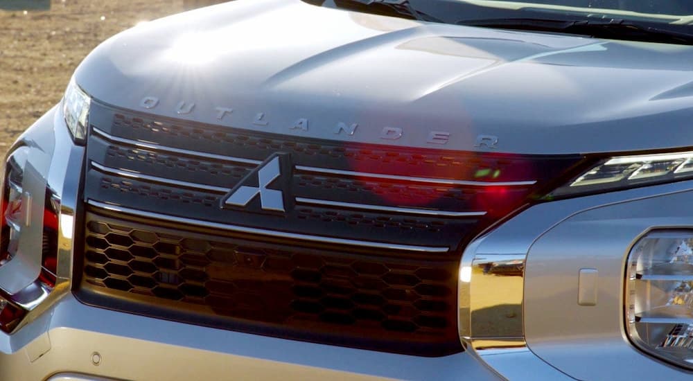 A close up of the hood and grille of a blue-grey 2023 Mitsubishi Outlander