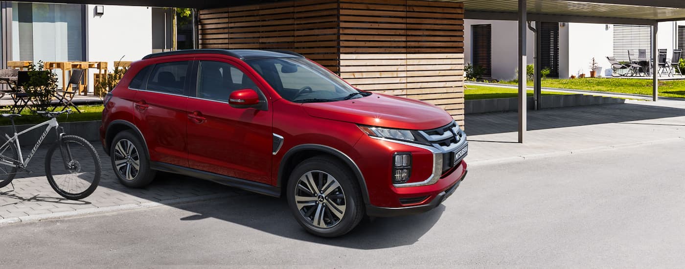 A red 2020 Mitsubishi RVR parked in a driveway next to a bicycle.