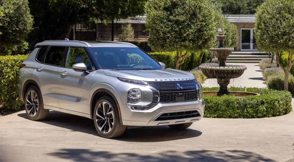 A silver 2024 Mitsubishi Outlander is parked in a driveway.