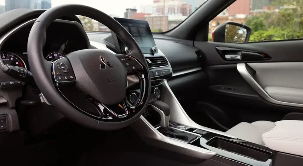 The black and white interior of a 2024 Mitsubishi Eclipse Cross is shown from the drivers side.