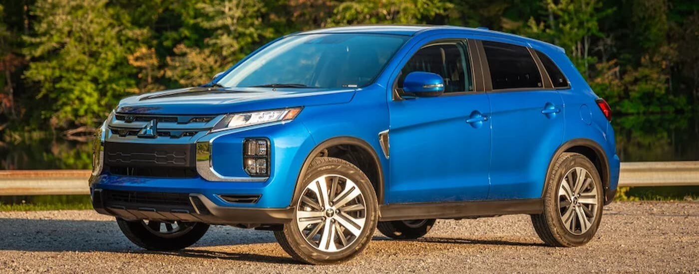 A blue 2024 Mitsubishi Outlander for sale near Alexandria is shown parked off-road.