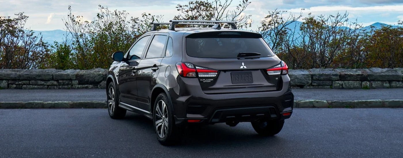 A black 2024 Mitsubishi Outlander Sport is shown parked near a stone wall.