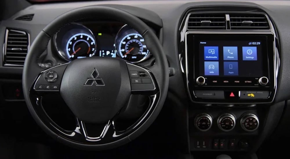 The black dash of a 2024 Mitsubishi Outlander Sport is shown from the driver's seat.