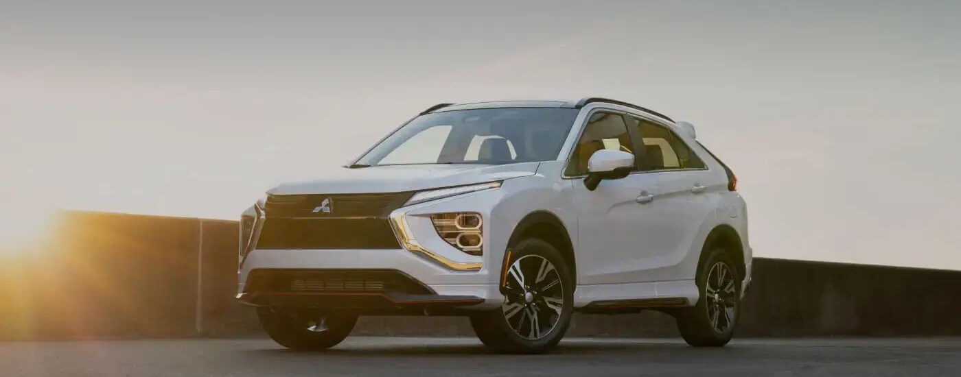 A white 2024 Mitsubishi Eclipse Cross is shown parked on a sunny day.