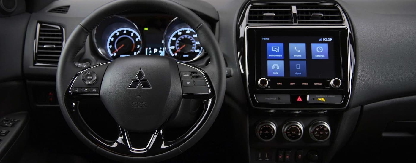 A close up of the steering wheel and infotainment center in a 2024 Mitsubishi Outlander Sport for Sale.