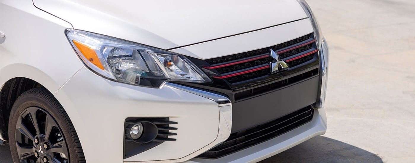 A close up of the front grille of a white 2022 Mitsubishi Mirage.