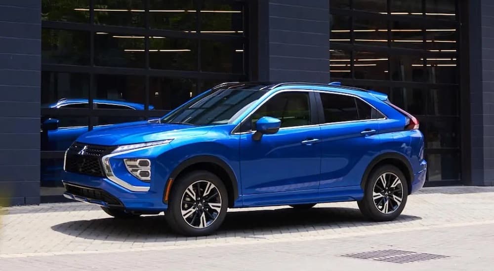 A blue 2024 Mitsubishi Eclipse Cross is shown from the side while parked on a city street.