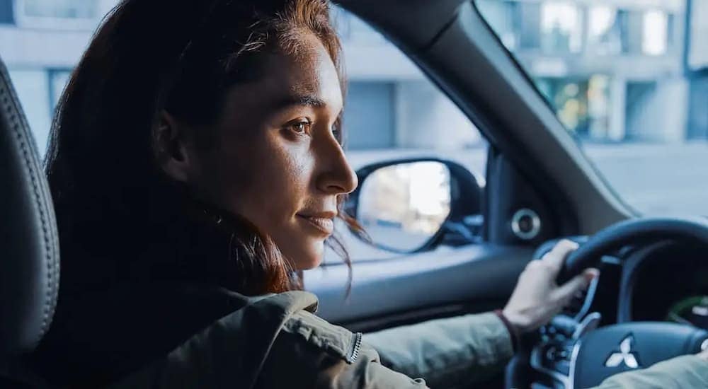 A woman driving a used 2022 Mitsubishi Outlander at the dealership.