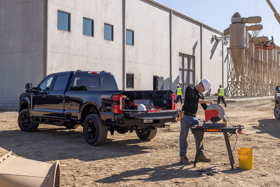 A black Ford Super Duty truck with the bed open on a construction site.