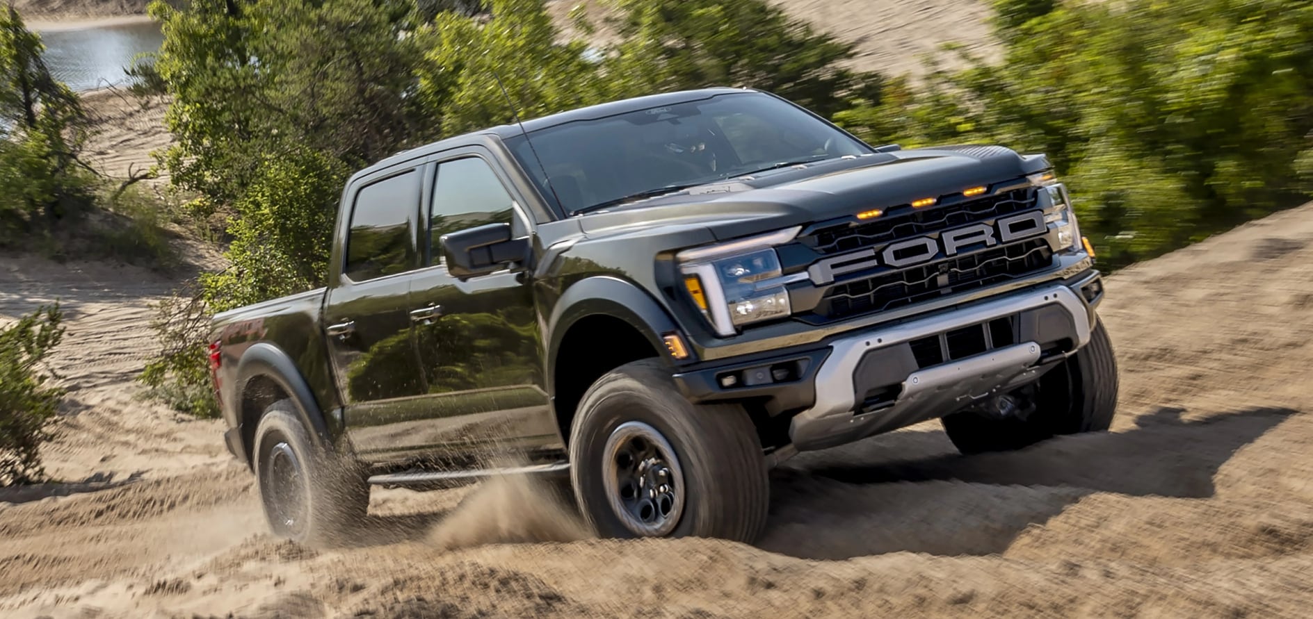 A black Ford F-150 driving up a hill.
