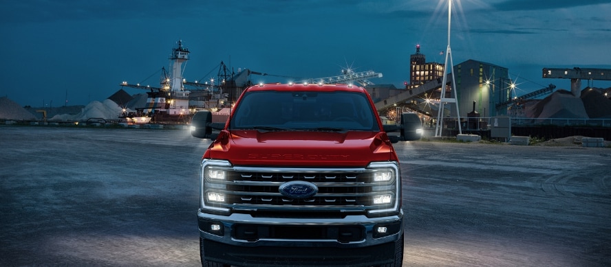 A front view of a red Ford Super Duty leaving a job site.