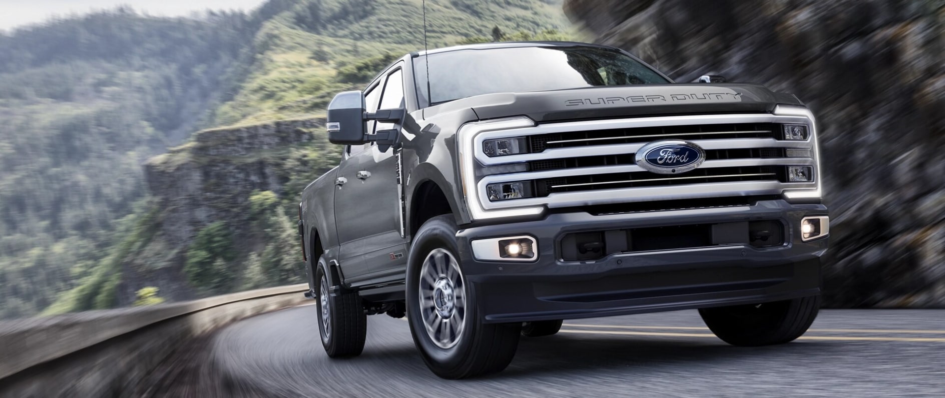 A front view of a gray Ford F-250 driving around a bend on a mountain road.