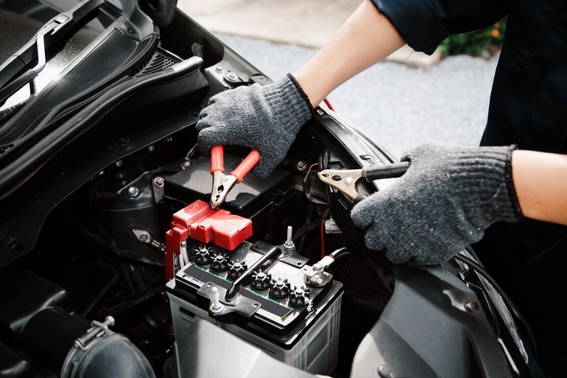 A technician attaching cables to a car battery.