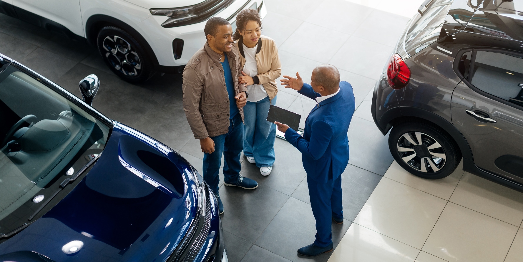 A car salesman speaking to a couple in a dealership.