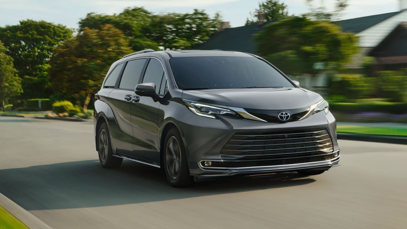 A gray Toyota Sienna driving through a suburban neighborhood.