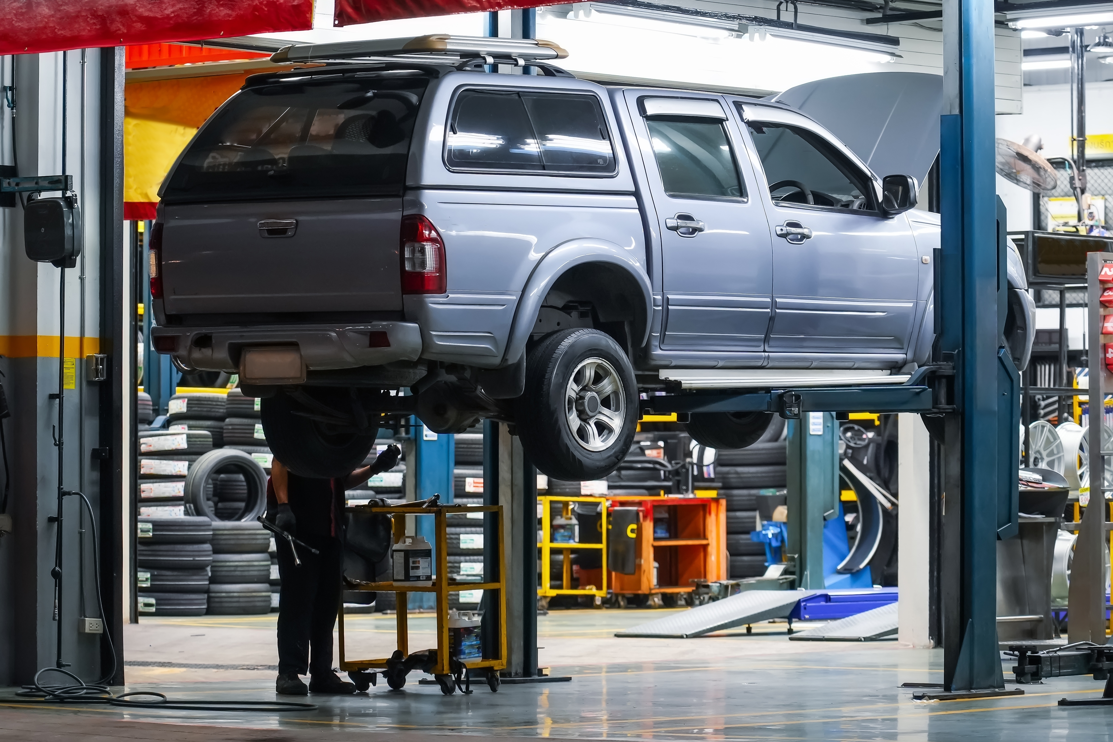 A blue truck being worked on in a service center on a raised platform.