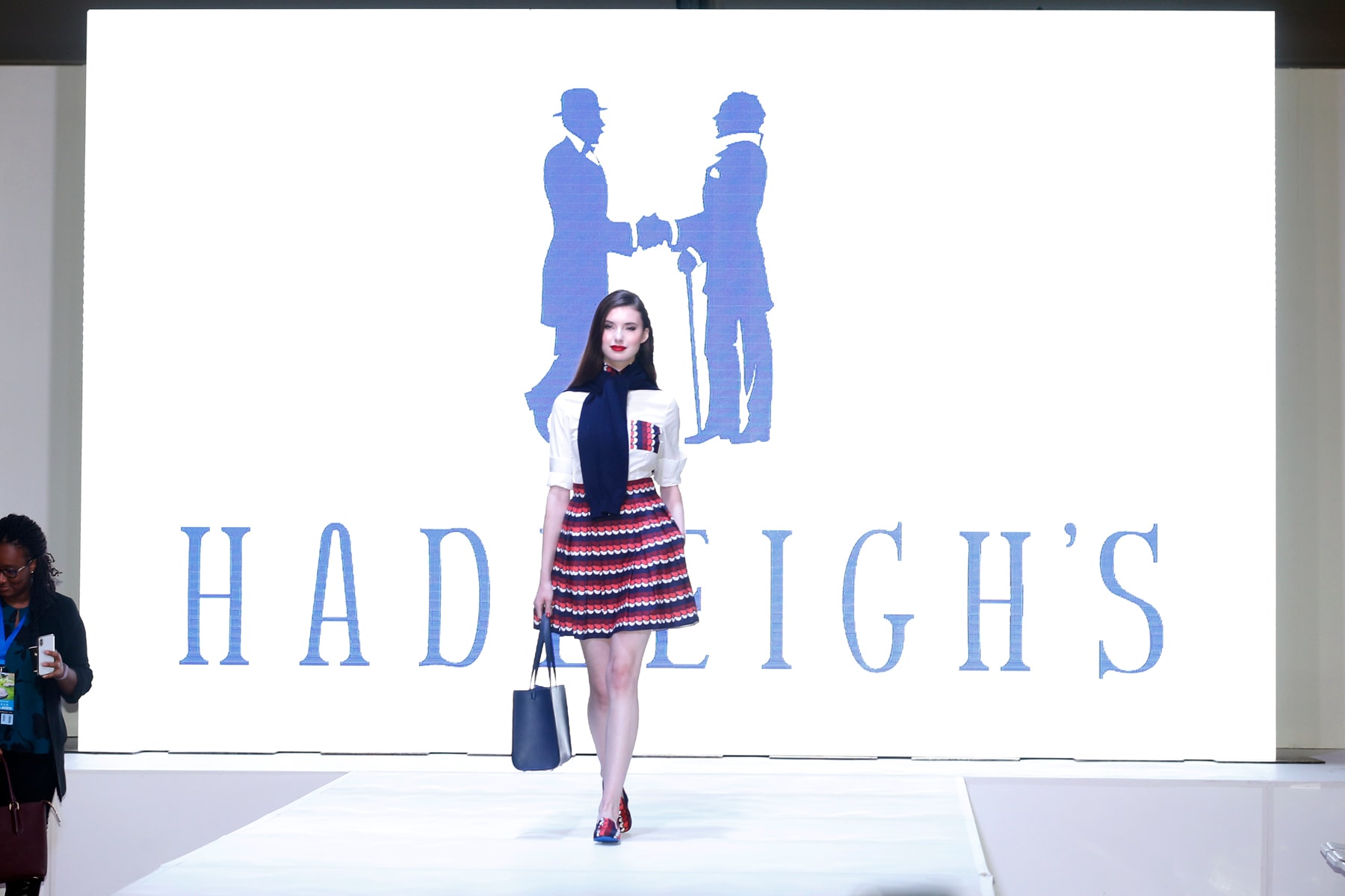 A model holding a handbag starts her walk down the runway at the fashion show at the Luxury Supercar Showcase