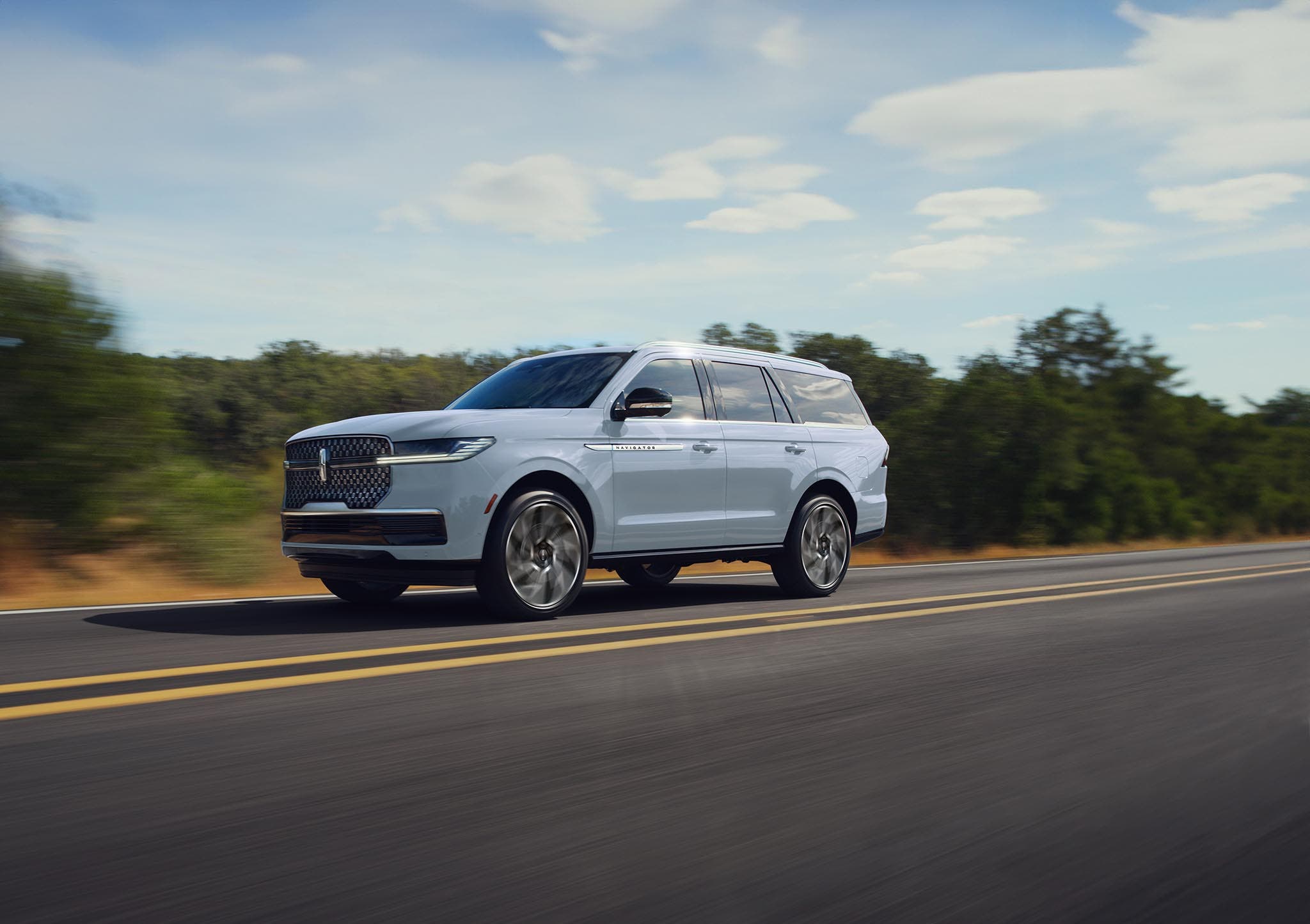 A Lincoln Navigator in Gray Mist driving along a two-lane highway