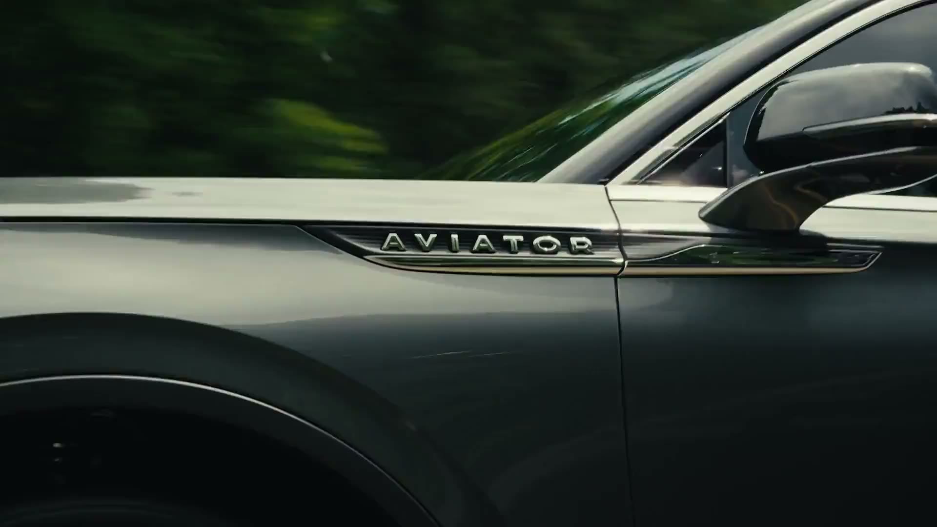 A Lincoln Aviator driving on a wooded road, seen close along its side with the Aviator badge on the front wing