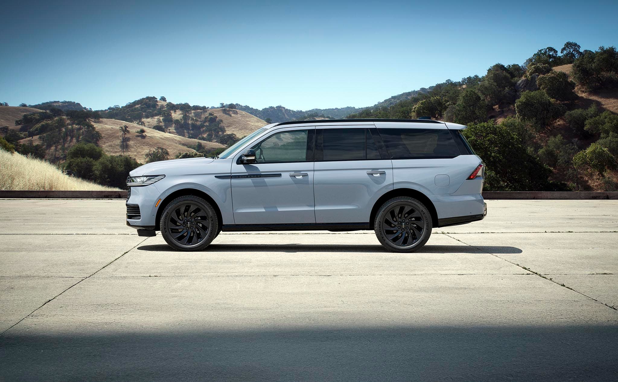 A Lincoln Navigator photographed in full side profile on a hilltop road, showing the whole length of the vehicle