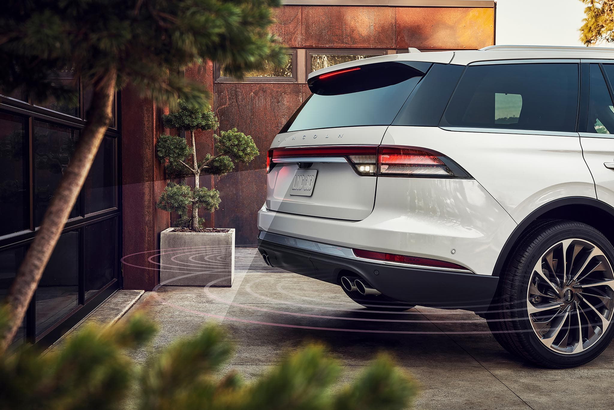 A Lincoln Aviator reversing out of a driveway with reverse brake assist detecting the path behind it