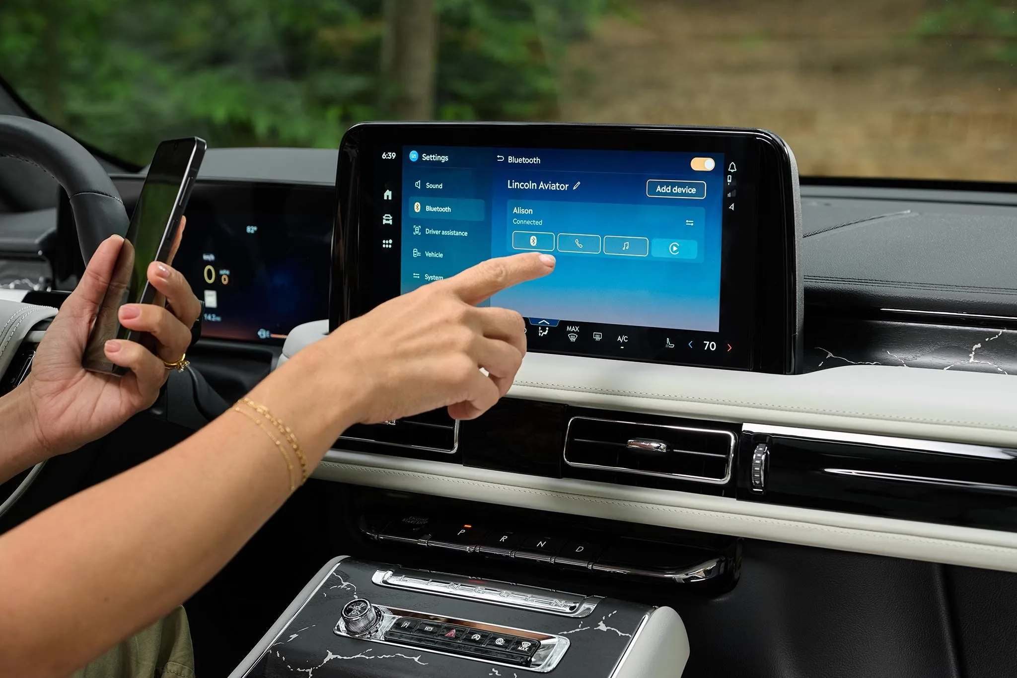 A hand reaching to the center touchscreen of a Lincoln Aviator