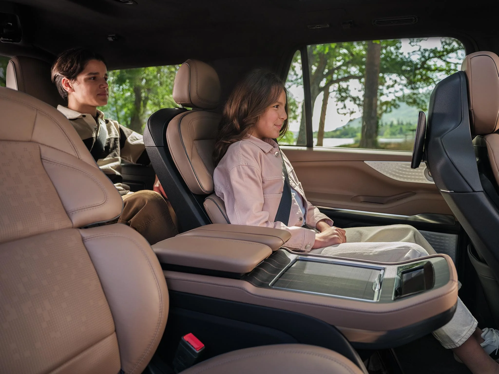 Two passengers in the second-row seats of a Lincoln Navigator, with the center console between them