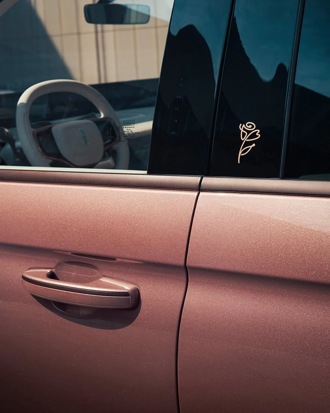 Close-up of the Navigator Black Label rose-metallic paint with a gold rose emblem on the pillar and flush door handle