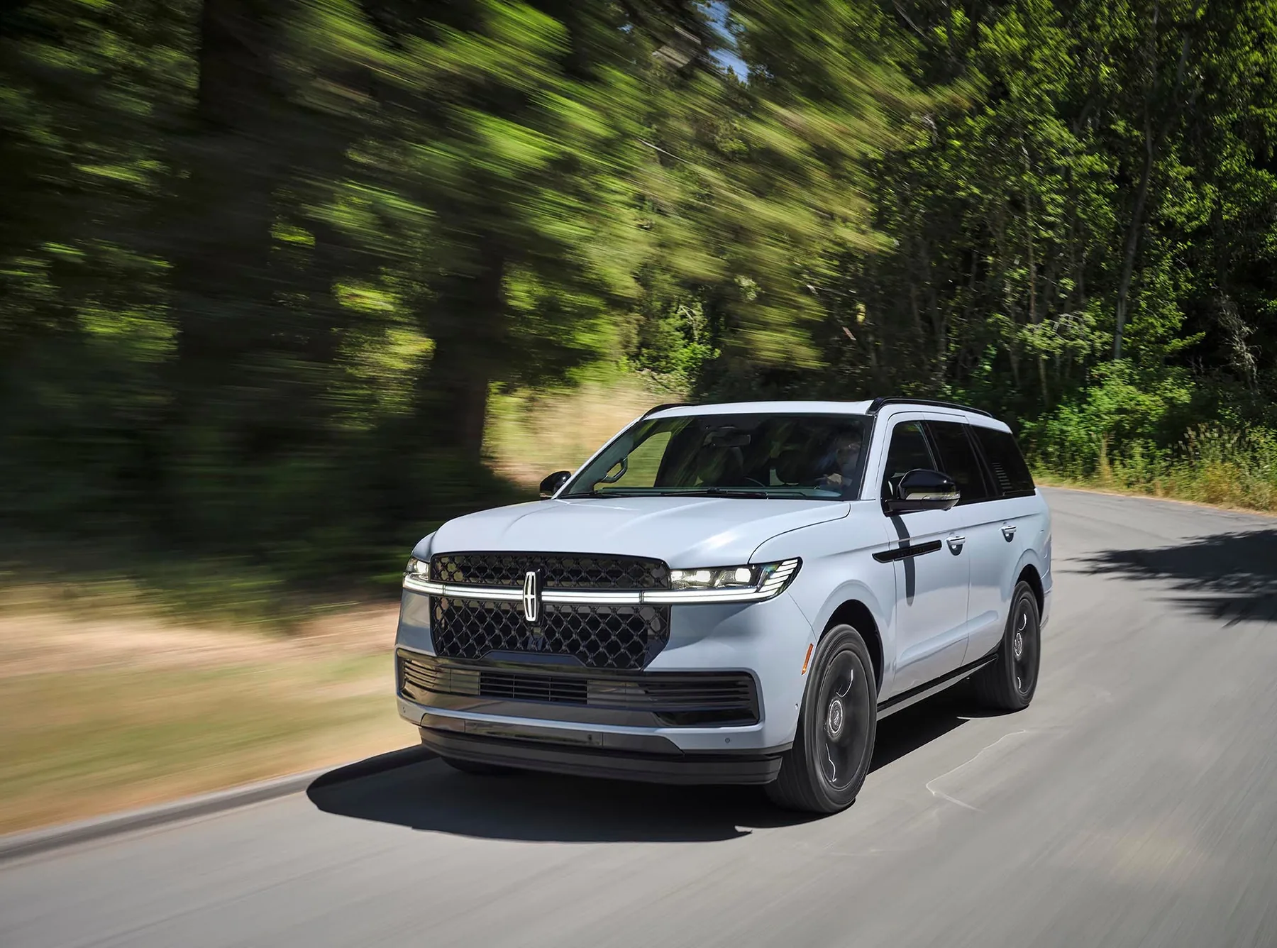 A white Lincoln Navigator Reserve on a wooded road