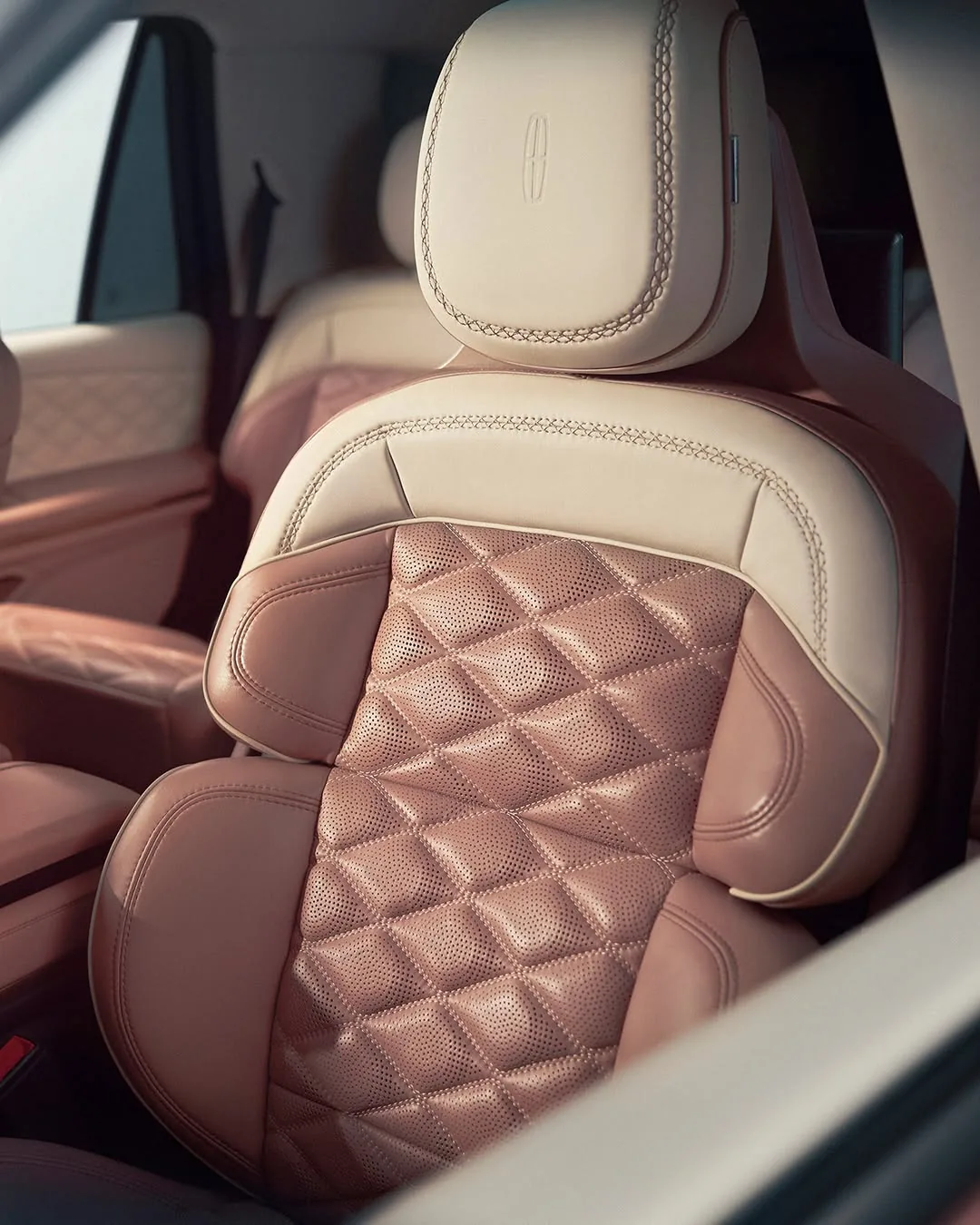 Two-tone cream and rose diamond-quilted perforated leather seat with an embossed Lincoln star on the headrest