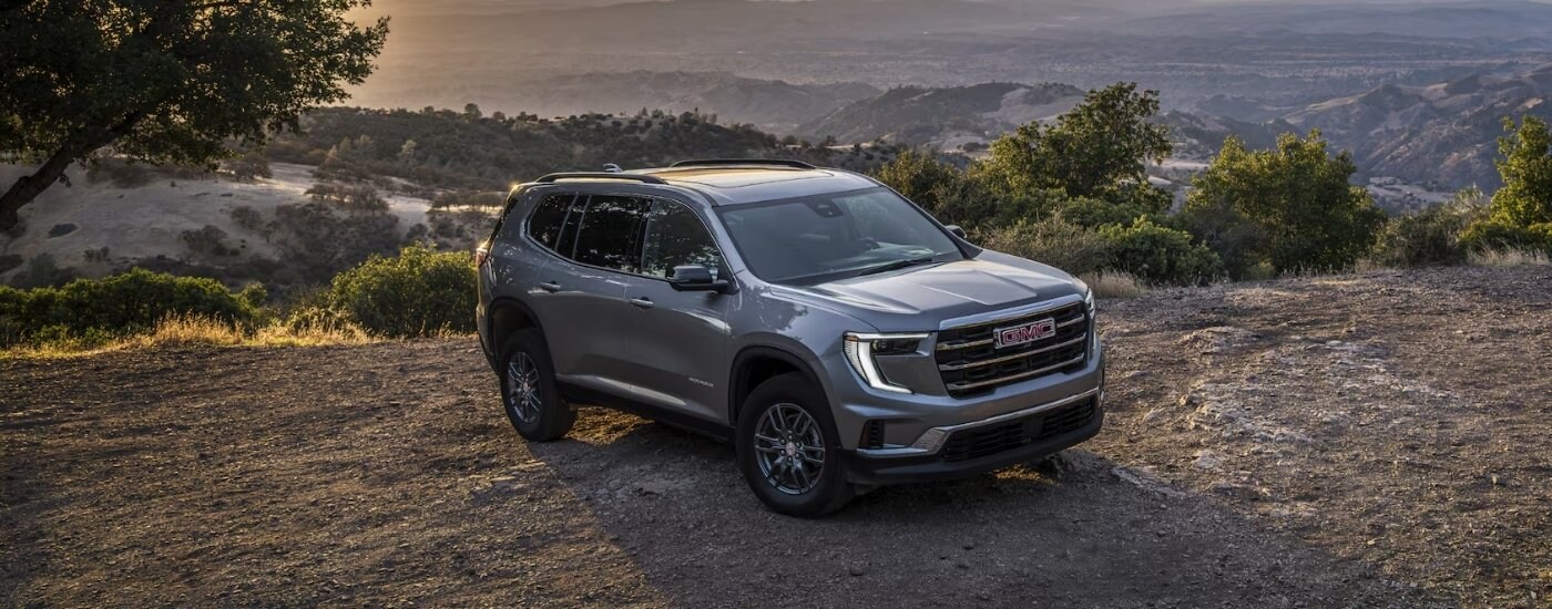 A gray 2025 GMC Acadia Elevation parked on dirt