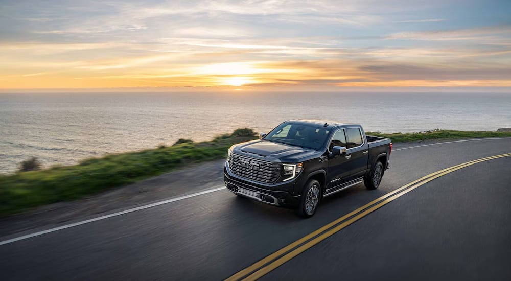 Black 2027 GMC Sierra 1500 driving around a bend.