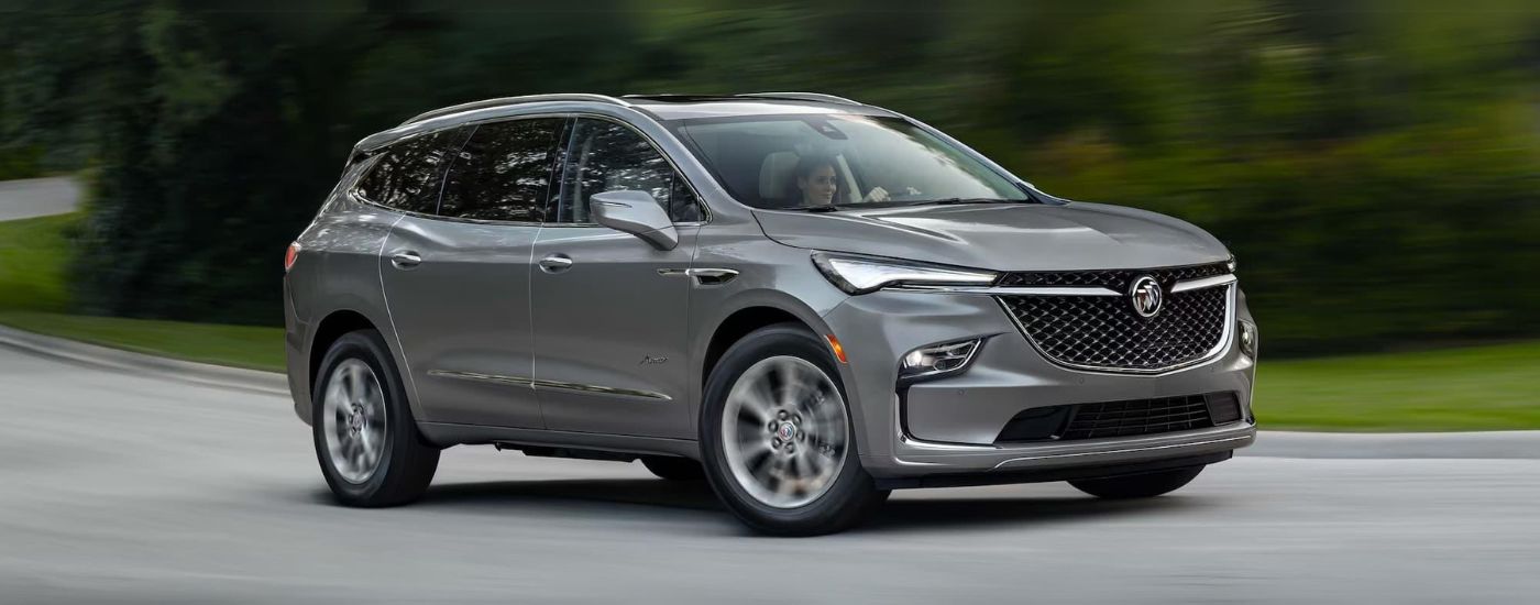 A silver 2024 Buick Enclave Avenir driving down a street
