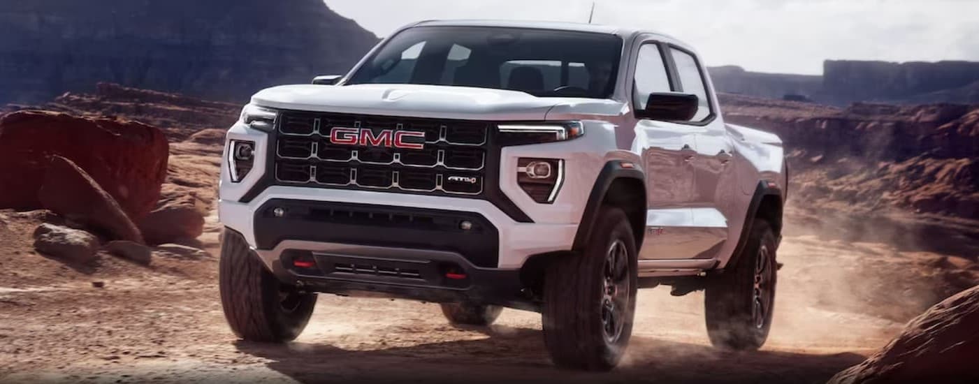 A white 2024 GMC Canyon AT4 driving offroad.
