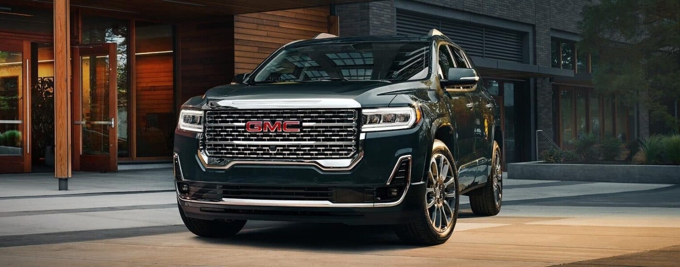 A black 2023 GMC Acadia Denali parked in front of a building