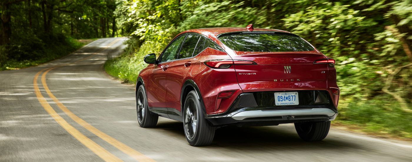 Rear of a red 2026 Buick Envista ST driving down an open road.
