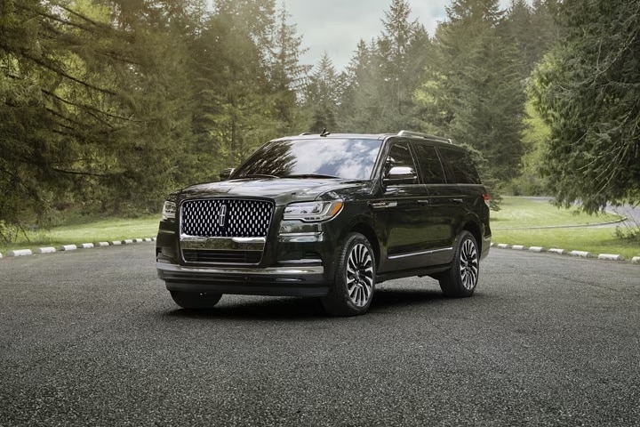 A black 2024 Lincoln Navigator parked outside by some trees.
