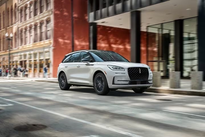 A white 2025 Lincoln Corsair Grand Touring Plug-in Hybrid driving in the city.