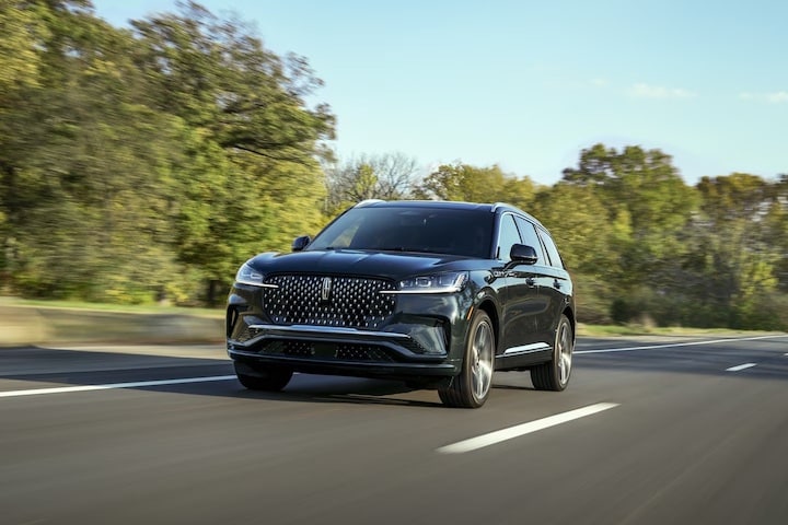 A black 2025 Lincoln Aviator driving on the road.