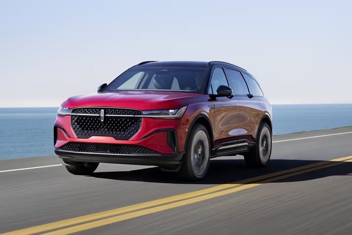 A red 2025 Lincoln Nautilus Hybrid driving on the road.